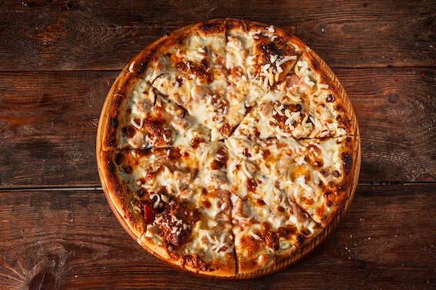 Apetitosa pizza de queso caliente en rodajas sobre una mesa de madera rústica. Comida italiana.