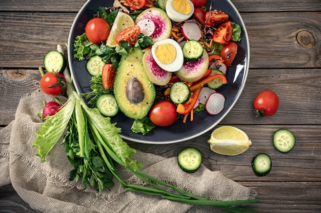 Apetitosa salada de legumes com ovos de abacate em um fundo de madeira