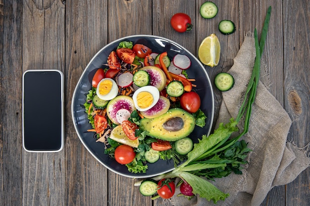 Apetitosa salada de legumes com ovos de abacate em um fundo de madeira