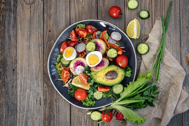 Apetitosa salada de legumes com ovos de abacate em um fundo de madeira