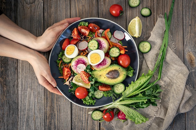 Apetitosa salada de legumes com ovos de abacate em um fundo de madeira