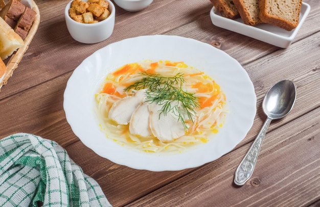 Foto apetitosa sopa de pollo con fideos y trozos de carne en un plato blanco sobre un fondo de madera oscura que sirve el chef