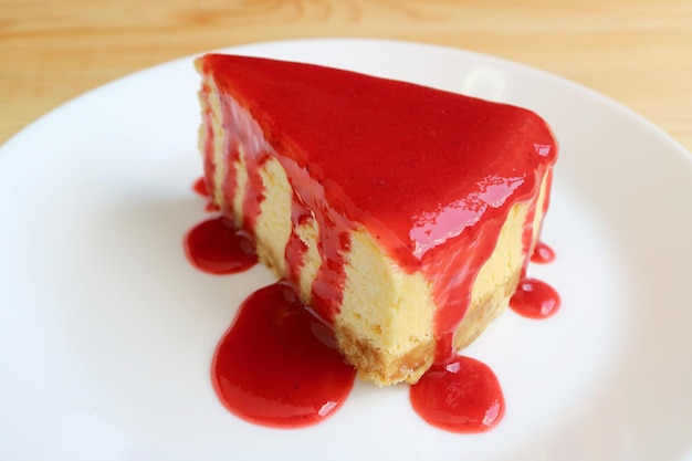 Apetitosa tarta de queso con salsa de frambuesa roja vibrante en la placa blanca.
