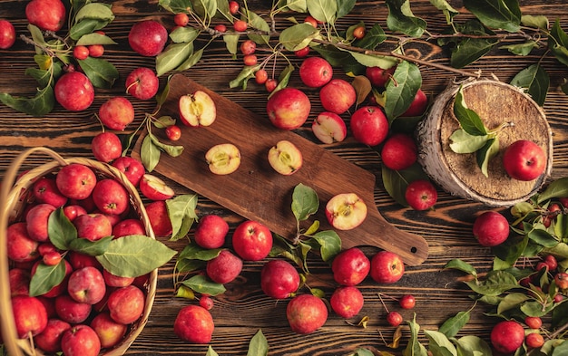 Apetitosas manzanas rojas con hojas verdes sobre una mesa de madera y en una cesta Cosecha fresca y estado de ánimo otoñal