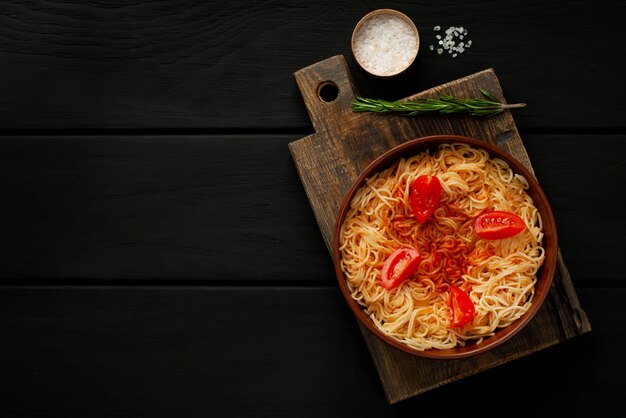 Apetitoso espaguete de massa italiana com molho de tomate, parmesão em um prato, tábua sobre um fundo de madeira. Vista de cima