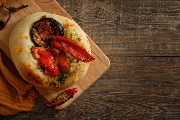 Apetitoso pão italiano focaccia com pimentão de berinjela e especiarias em uma mesa de madeira escura