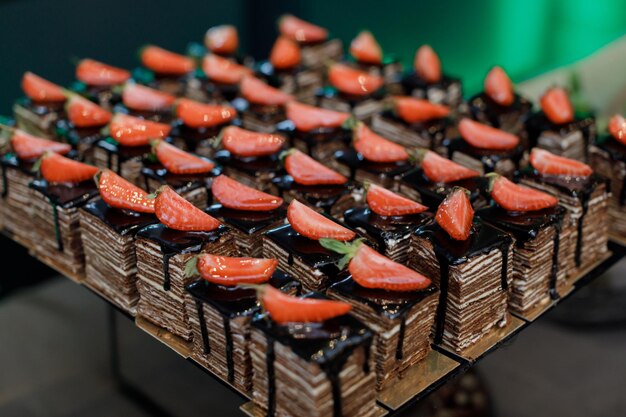 Apetitoso pastel de chocolate cortado en trozos cuadrados decorado con rodajas de fresa