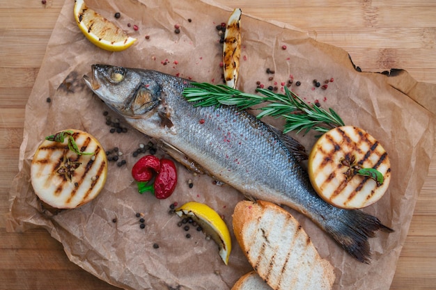 Apetitoso peixe sibas com verduras e legumes em um fundo de madeira