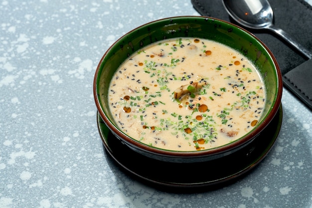 Apetitoso plato de cocina pan-asiática - sopa de miso de queso en un recipiente verde sobre un fondo gris