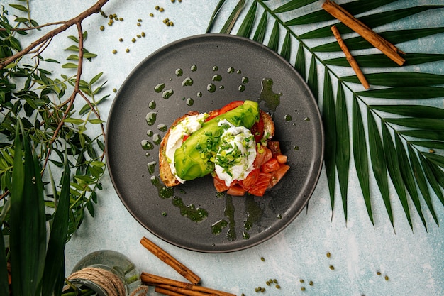 Apetitoso sándwich de aguacate con salmón y huevo escalfado para el desayuno