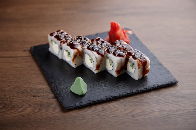 Apetitoso sushi en un plato de piedra sobre una mesa de madera oscura.