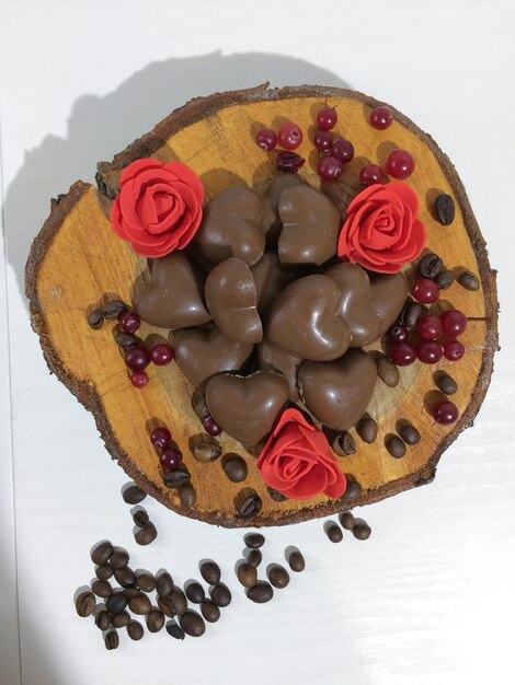 Apetitosos dulces de chocolate sobre un fondo blanco Sobre un corte de madera Con flores y granos de café