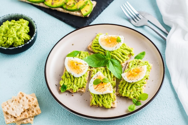 Apetitosos sándwiches de pan crujiente con aguacate y huevo cocido en un plato Dieta flexitariana alimentación saludable