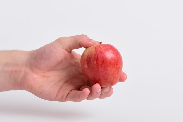 Apfel in frischer und saftiger Farbe Gesundheits- und Ernährungskonzept Männliche Hand hält hellroten Apfel Apfelfrucht isoliert auf hellgrauem Hintergrund