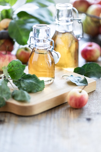 Apfelessig. Flasche organischer Essig oder Apfelwein des Apfels auf hölzernem Hintergrund. Gesunde Bio-Lebensmittel. Mit textfreiraum.