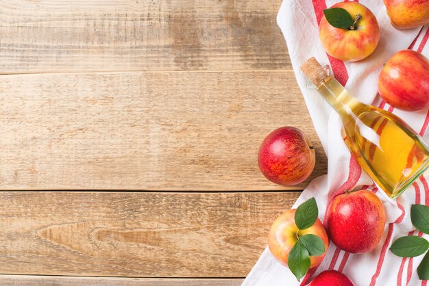 Apfelessig in der Flasche mit Apfel auf Holz