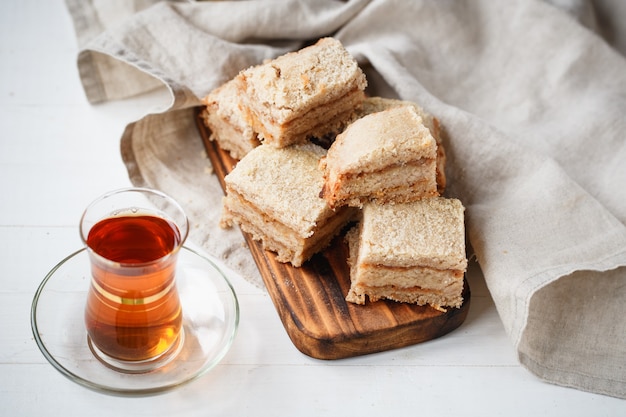 Apfelkuchen auf Holzbrett mit Tee in Beigetönen