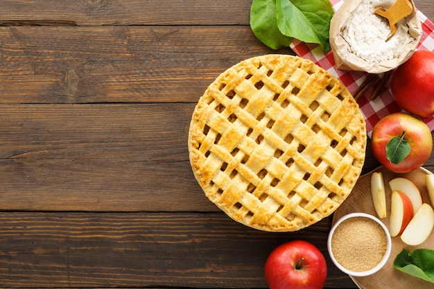 Apfelkuchen mit Gitterplatte und Zutaten auf Holztisch