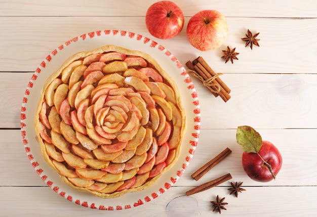 Apfelkuchen mit Zimt auf einer Platte und Äpfeln und Zimt