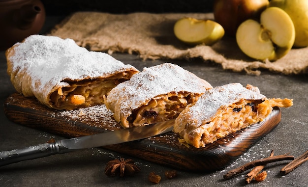 Apfelkuchen - Strudel oder Apfelstrudel, geschnittener Kuchen mit Äpfeln und Gewürzen auf einem grauen Tisch, Nahaufnahme, selektiver Fokus. Traditionelle Kuchen der europäischen Küche