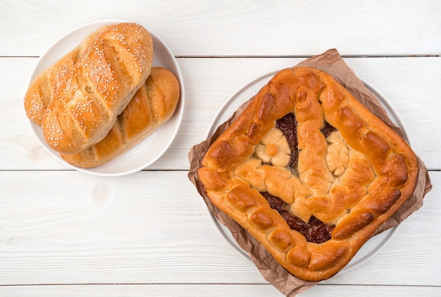 Apfelkuchen und frische Brötchen auf einem hellen Hintergrund. Draufsicht mit Platz zum Kopieren.