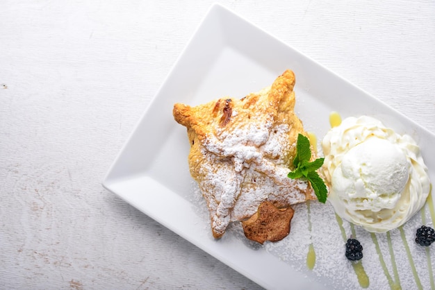 Apfelstrudel mit Eis auf einem hölzernen Hintergrund Ansicht von oben Freier Platz für Text