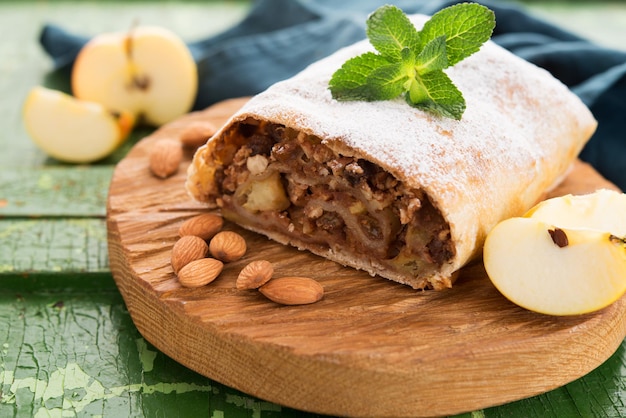 Apfelstrudel mit Nüssen und Rosinen auf einem Holzbrett, Nahaufnahme