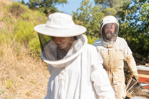 Apicultor y asistente trabajando en un campo