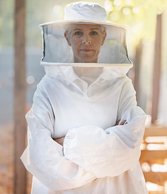 Foto apicultor de retrato e mulher com os braços cruzados na fazenda se preparando para o trabalho apicultura de liderança e agricultor de pequenas empresas e trabalhador maduro se preparando para a colheita de mel em traje de segurança