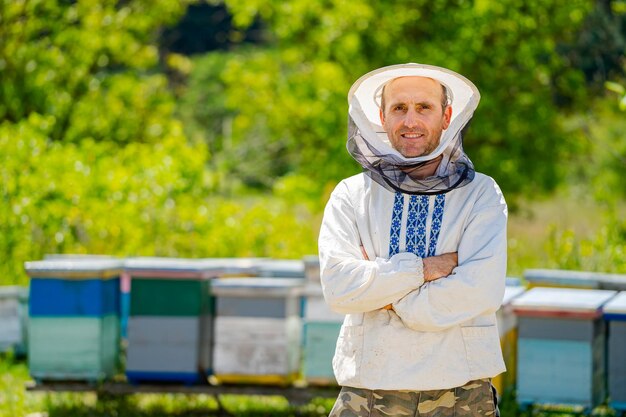 Apicultor em roupas de trabalho de proteção Fundo de colmeias no apiário Trabalha nos apiários na primavera