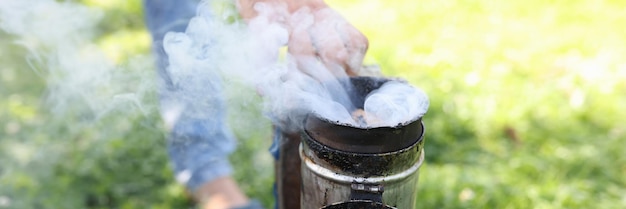 Apicultor fumando abejas de miel con fumador de abejas en concepto de colmenar