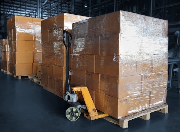 Apilado de cajas de paquetes en palés de madera y transpaletas manuales en el almacén de almacenamiento Cajas de envío Exportación de carga Importación