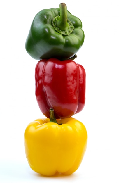 Apilado de paprika verde, rojo y amarillo colorido de los paprikas en el fondo blanco
