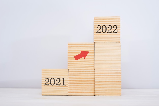 Apilamiento de bloques de madera como escalera. Concepto de trayectoria profesional de escalera para el proceso de éxito del crecimiento empresarial con la flecha que se mueve hacia arriba del año 2021 al 2022