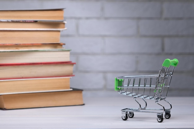 Apilar con libros y mini carrito de compras en la tarifa de matrícula del concepto de educación de mesa