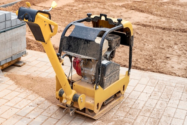 Apisonador vibratorio con placa vibratoria en un sitio de construcción Compactación del suelo antes de colocar losas de pavimentación Primer plano