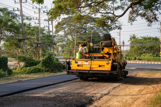 Apisonadora amarilla o compactador de suelo trabajando en la carretera de asfalto en el sitio de construcción