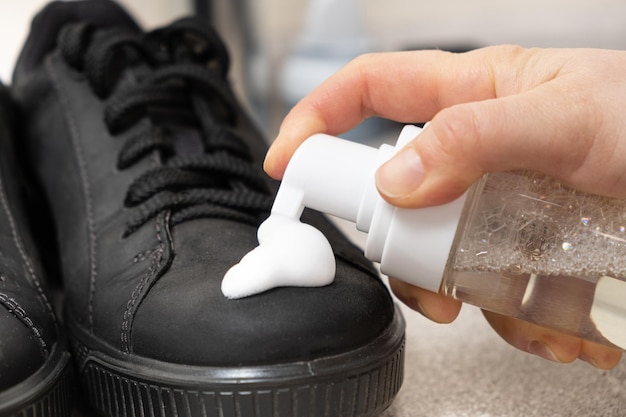 Foto aplicação de espuma de limpeza de uma garrafa em sapatos masculinos nobuck