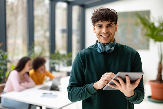 Aplicación para el conocimiento alegres estudiantes europeos que usan tableta para una lección de video que estudia con amigos