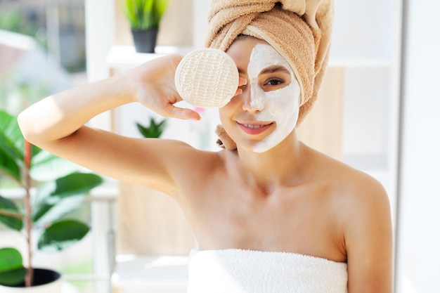 Aplicación de mascarilla facial blanca con cepillo en casa.