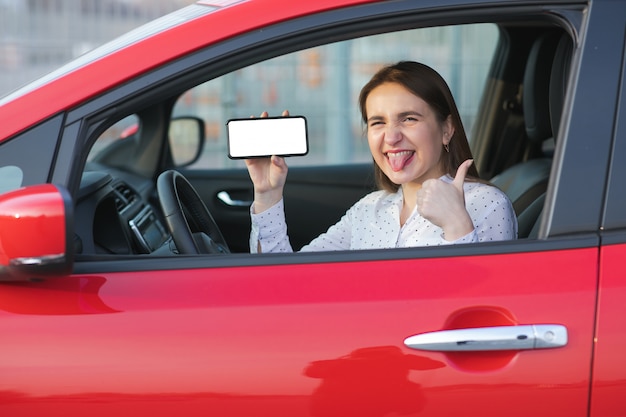 Aplicación móvil para transporte ecológico. Carga de coche eléctrico y mirando la aplicación en el teléfono móvil. Cerca de la pantalla del teléfono inteligente. Mano que sostiene el dispositivo inteligente con pantalla en blanco.