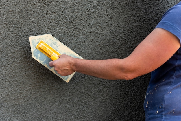 Aplicación de yeso decorativo en pared mediante herramienta de construcción.