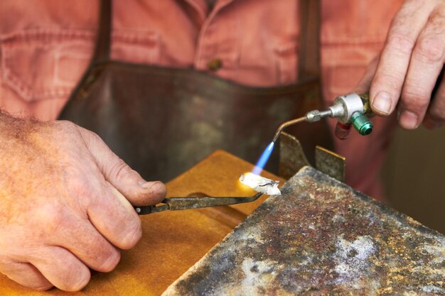 Foto aplicando calor - fabricação de joias. vista recortada de um joalheiro de fabricação trabalhando com um pequeno maçarico de acetileno.