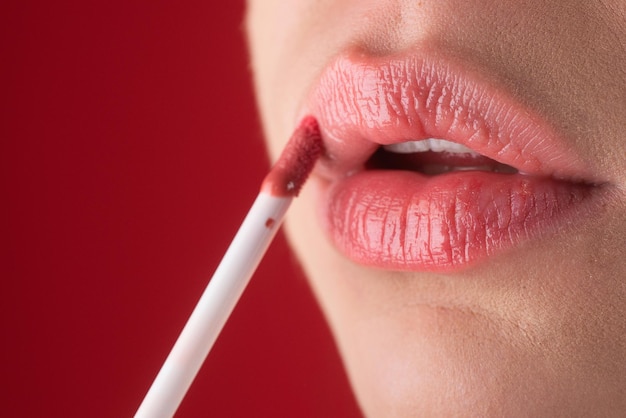 Aplicando lápiz labial om labios regordetes y sexys pintando labios con lápiz labial brillante de cerca mimando los labios