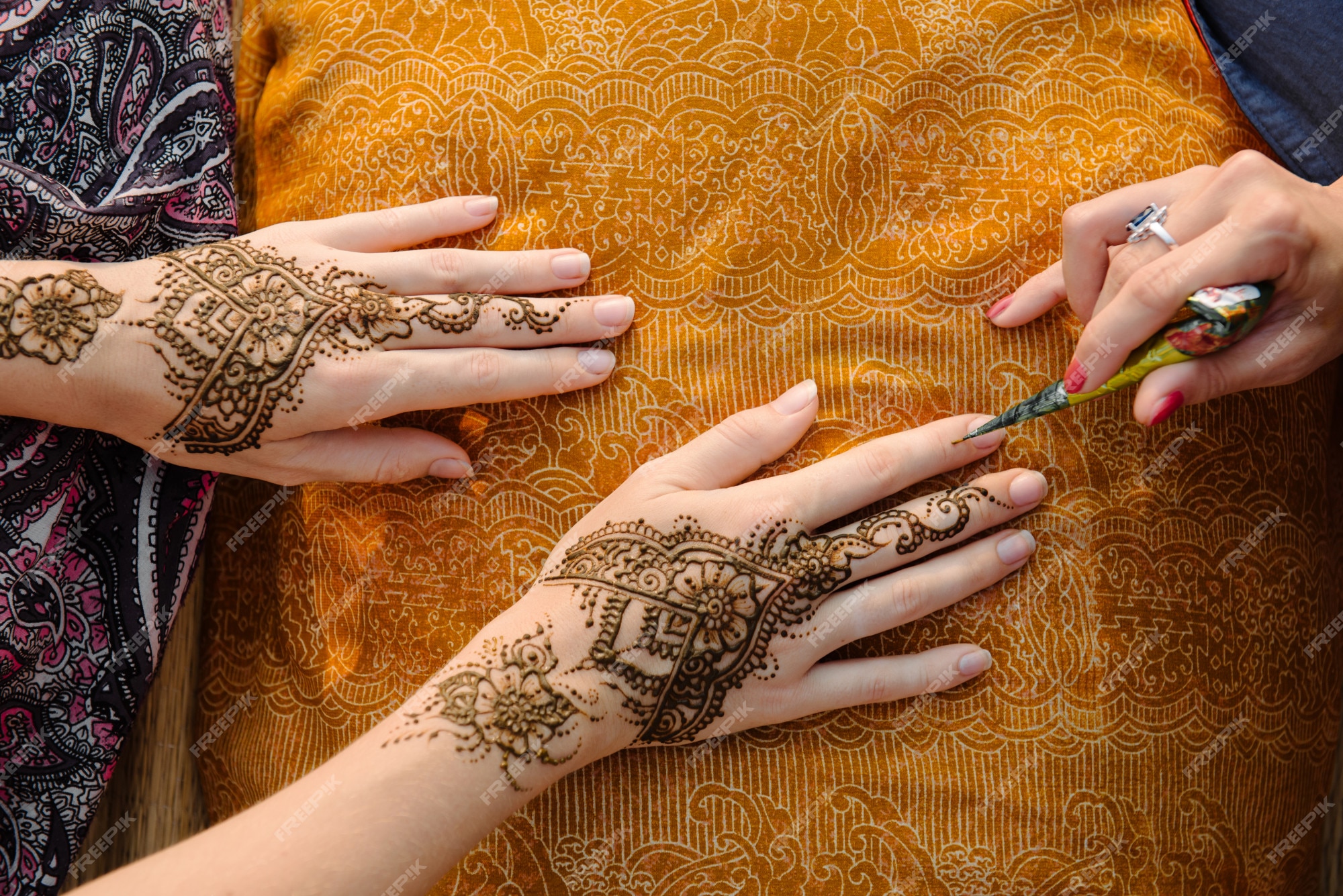 Artista aplicando tatuagem de henna mehndi na mão feminina