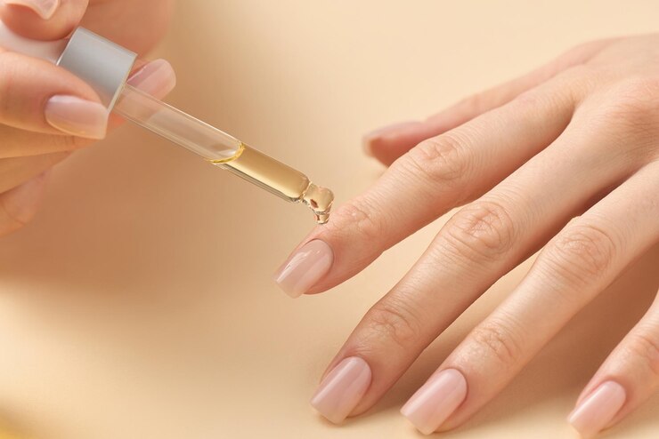 Aplicar aceite nutritivo para mejorar la salud y el aspecto de las uñas durante una rutina de cuidado personal en casa