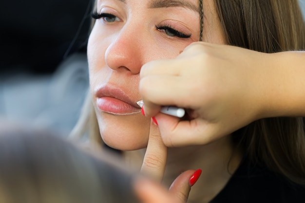 Aplicar el contorno de los labios con un lápiz blanco antes del procedimiento de maquillaje de labios permanente.