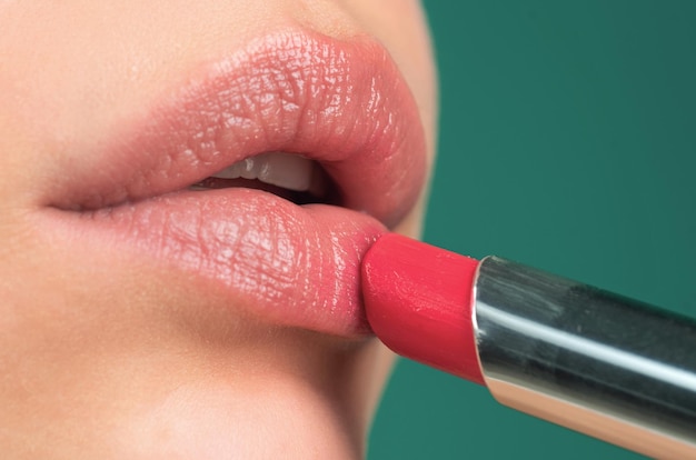 Aplicar lápiz labial Pintar labios con lápiz labial brillante de cerca Mimar el concepto de corrección de labios Lápiz labial brillante en el labio regordete completo Mano de mujer aplicar lápiz labial