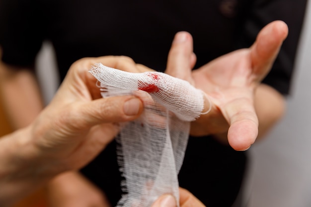 Aplicar uma bandagem na ferida do dedo de um homem. O homem negligenciou as precauções e cortou a mão. Trauma doméstico. Acidentes de trabalho.