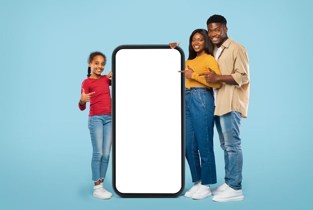 Aplicativo móvel legal Família negra feliz apontando para um grande smartphone gigante com aplicativo ou site de promoção de maquete